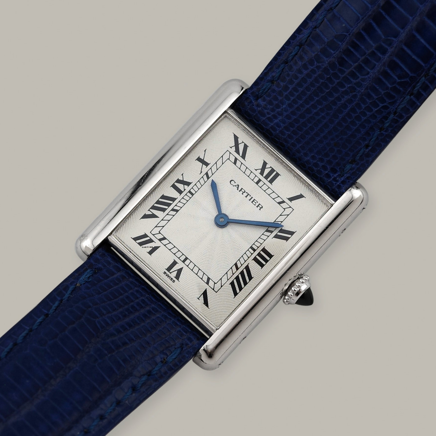 Cartier watch with blue strap on a gray background